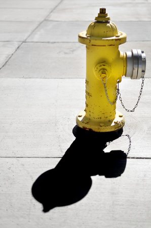 Detail of yellow fire hydrant with shadow on sidewalk for safetyの写真素材