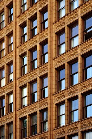 Building in city with windows reflecting blue sky lightの写真素材