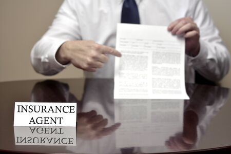 Insurance agent sitting at desk holding blank contractの写真素材