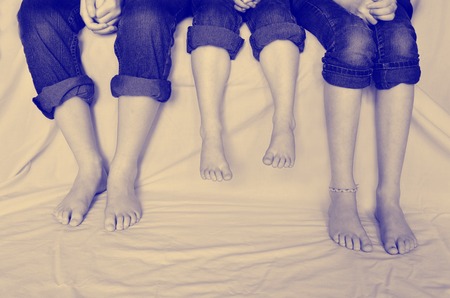  family sitting with jeans rolled up sharing fun moment of happiness together bare feetの写真素材