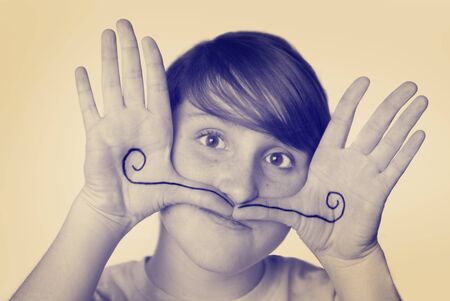  young girl with mustache drawn on hands silly faceの写真素材
