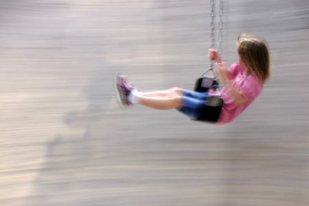 Little girl playing on swing set at a parkの写真素材