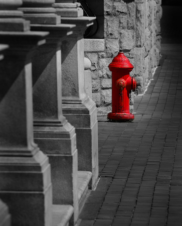 Red fire hydrant on sidewalk next to old stone buildingの写真素材