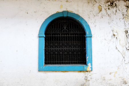 Detail of wall with old window painted blue handworked iron barsの写真素材