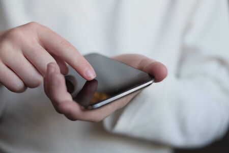 Person holding smart phone in hands to communicate and textの写真素材