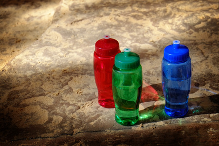 Detailed red, green, and blue bottles on rought rocksの写真素材