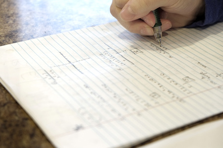 Child doing homework writing on paper with pencilの写真素材