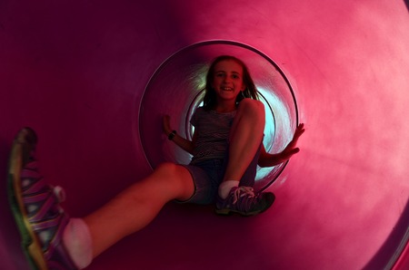 Young Girl sliding down tube slide at parkの写真素材