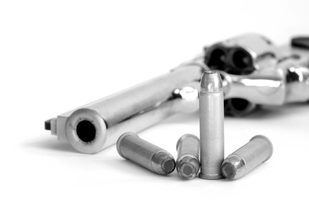 Closeup of powerful handgun with bullets on white  surface