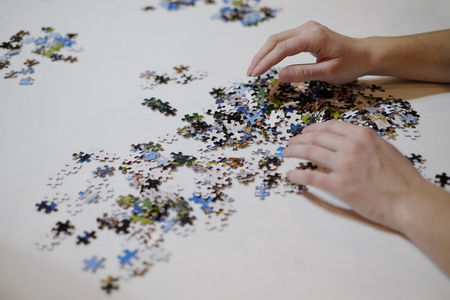 Hands putting puzzle together on white table の写真素材