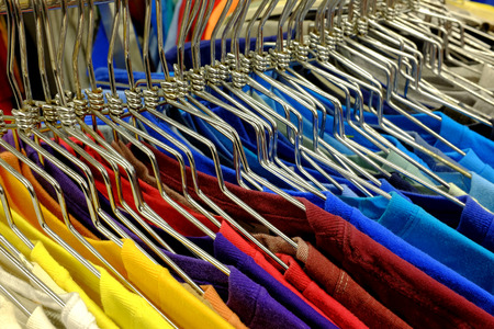 Colored shirts on hangers set on a rack to sell in the storeの写真素材