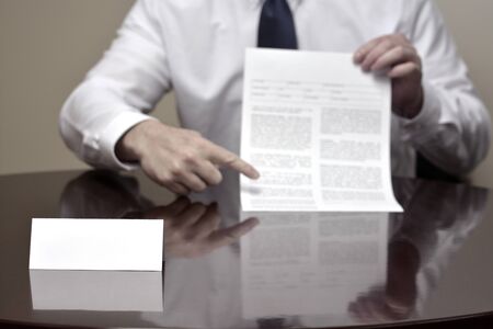 Businessman at desk with papers and card making hand gesturesの写真素材