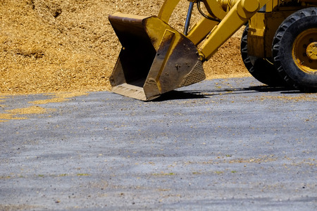 Heavy equipment backhoe or bulldozer with pile of dirt wood chipsの写真素材