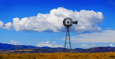 Windmill on hillside in countryside rural America with sky and clouds