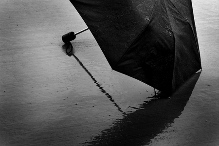 Wet black umbrella in stormy rainy weather providing shelter from the rain stormの写真素材