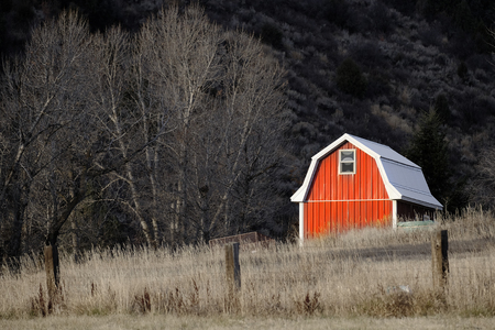 Old red barn in field late fall or autumn brown grass and fenceの写真素材