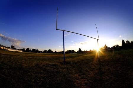 Football goalposts goal posts uprights at sunset with sun sky and bleachersの写真素材