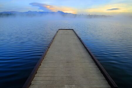 Dock floating on lake with early morning mist