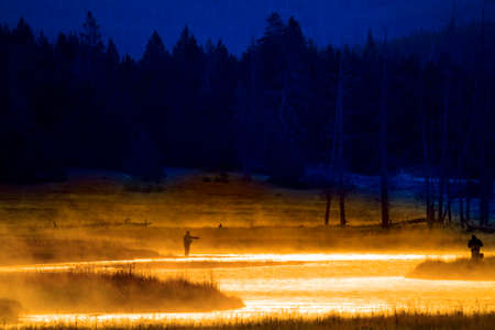 Silhouette of Fishing Flyfishing rod reel in river with golden sunlightの写真素材