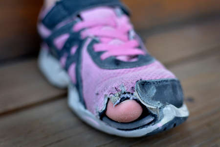 Homeless child wearing old worn out shoes on feet with holes in them toes sticking outの写真素材