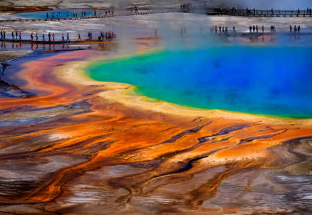 Grand Prismatic Spring in Yellowstone National Park with tourists viewing the spectacular natural sceneの写真素材