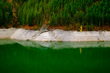 Lakeside lake forest forrest in mountains by water reflections of Autumn fall treesの写真素材