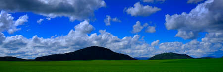 Green field grass mountain hill and blue sky with cloudsの写真素材