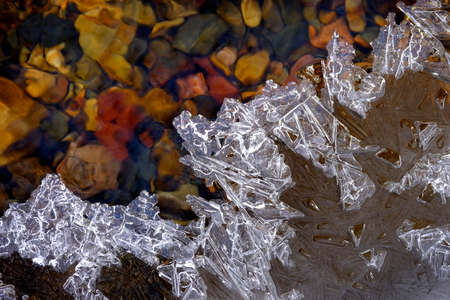 Frozen ice on creek stream with stones and rocks wet wilderness
