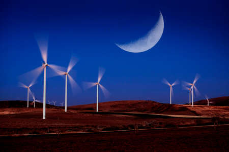 Windmill wind turbines spinning fast in wind with moon light