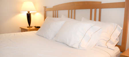 Group of several white pillows on a bed with headboardの写真素材