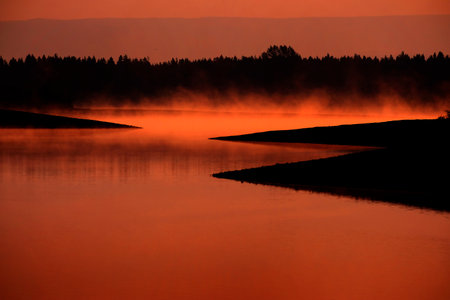 Misty morning on the lake with steam rising from water sunlightの写真素材