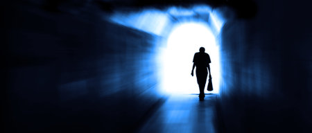 Long tunnel walkway with person at the end in motion ending depression towards the lightの写真素材