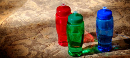 Detailed red, green, and blue bottles on rought rocksの写真素材