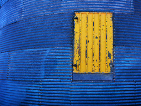 Painted yellow door on steel grain silo granary building textureの写真素材