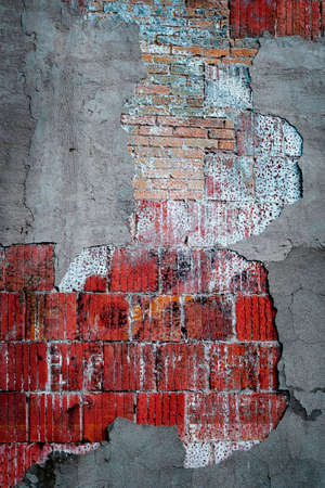Old worn plaster cracked and falling on building wall with texture and colorsの写真素材