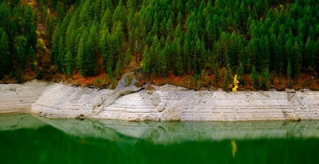 Lakeside lake forest forrest in mountains by water reflections of Autumn fall treesの写真素材