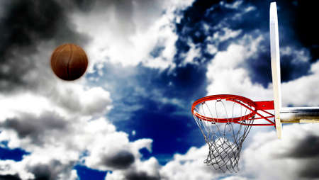 Outdoor basketball with clouds and sky and shot to the hoop ball blurred motion actionの写真素材