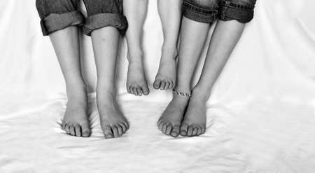 Family sitting with jeans rolled up sharing fun moment of happiness together bare feet on white backgroundの写真素材