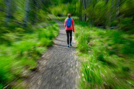 Woman hiking in mountains wilderness exploring and exercising zoom blurの写真素材