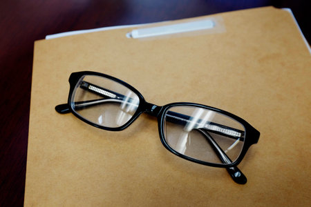 Black glasses on top of a work folder or file on a desk school or businessの写真素材