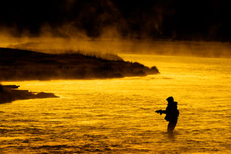 Silhouette of Fishing Flyfishing rod reel in river with golden sunlightの写真素材