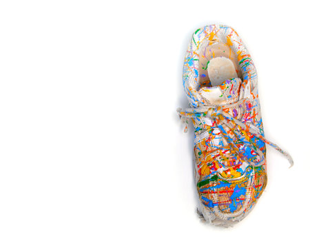 Old worn white shoes sneakers splattered in colorful paintの写真素材
