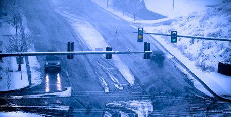 Traffic light on road during winter storm with cars drivingの写真素材