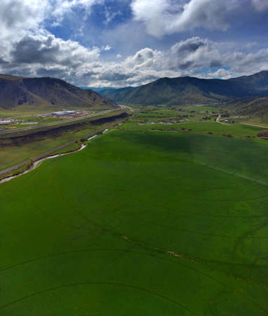 Aerial View from a Drone Flying above Green Valley With Farm Fields Growing Crops Irrigation Pivot Sprinklersの写真素材