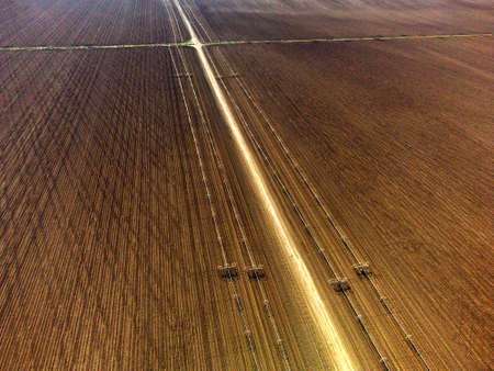 Furrowed farm field plowed with sprinklers spraying water irrigation for farming