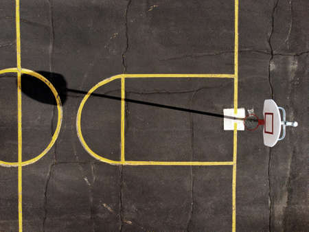 Aerial view from a drone flying above an outdoor urban basketball park with yellow lines and shadowsの写真素材