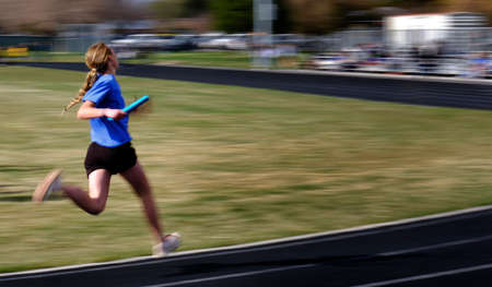 Person running a relay race on a track with blurred legs speed blurの写真素材