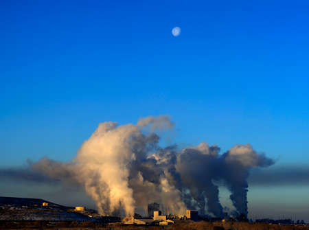 Factory or energy plant producing pollution and smoke into the air of blue sky with moonの写真素材