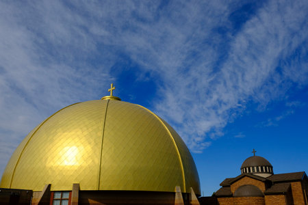 Gold dome on a christian church with cross and blue sky clouds in the backgroundの写真素材