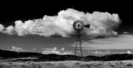 Windmill on hillside in countryside rural America with sky and clouds black and whiteの写真素材
